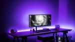 Computer on a desk in a room with purple lights