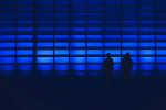 Two silhouettes of people standing in front of blue lights